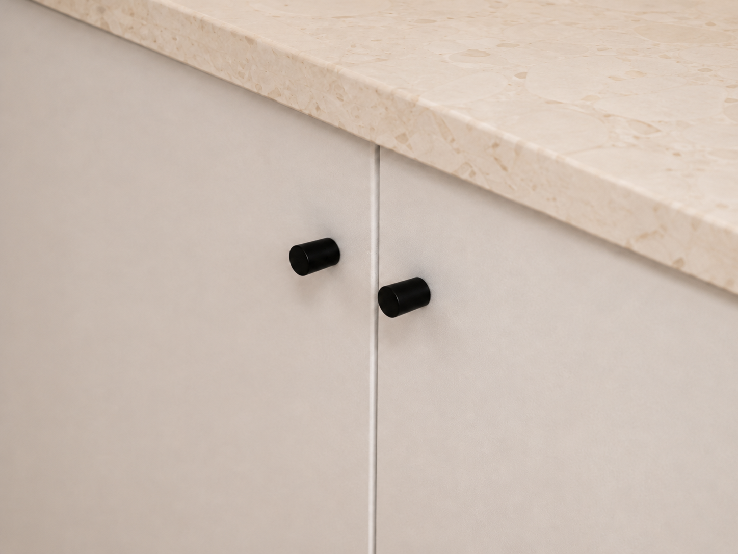 A sculpted stone island anchors the room, combining durability with soft, rounded edges for a confident yet understated presence.